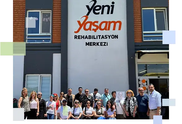 Yeni Yaşam Rehabilitasyon Merkezi binası önünde kurum idarecileri ve personelinin yer aldığı toplu kurumsal hatıra fotoğrafı.