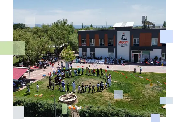 Yeni Yaşam Rehabilitasyon Merkezi bahçesinde öğrenci ve eğitmenlerin el ele tutuşarak geniş bir daire oluşturduğu sosyal etkileşim ve grup oyunu anı.
